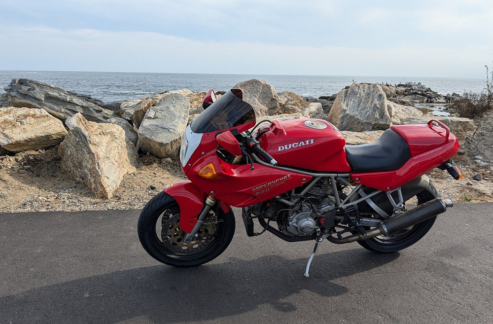 Ducati 900 CR parked by a sea wall at the ocean